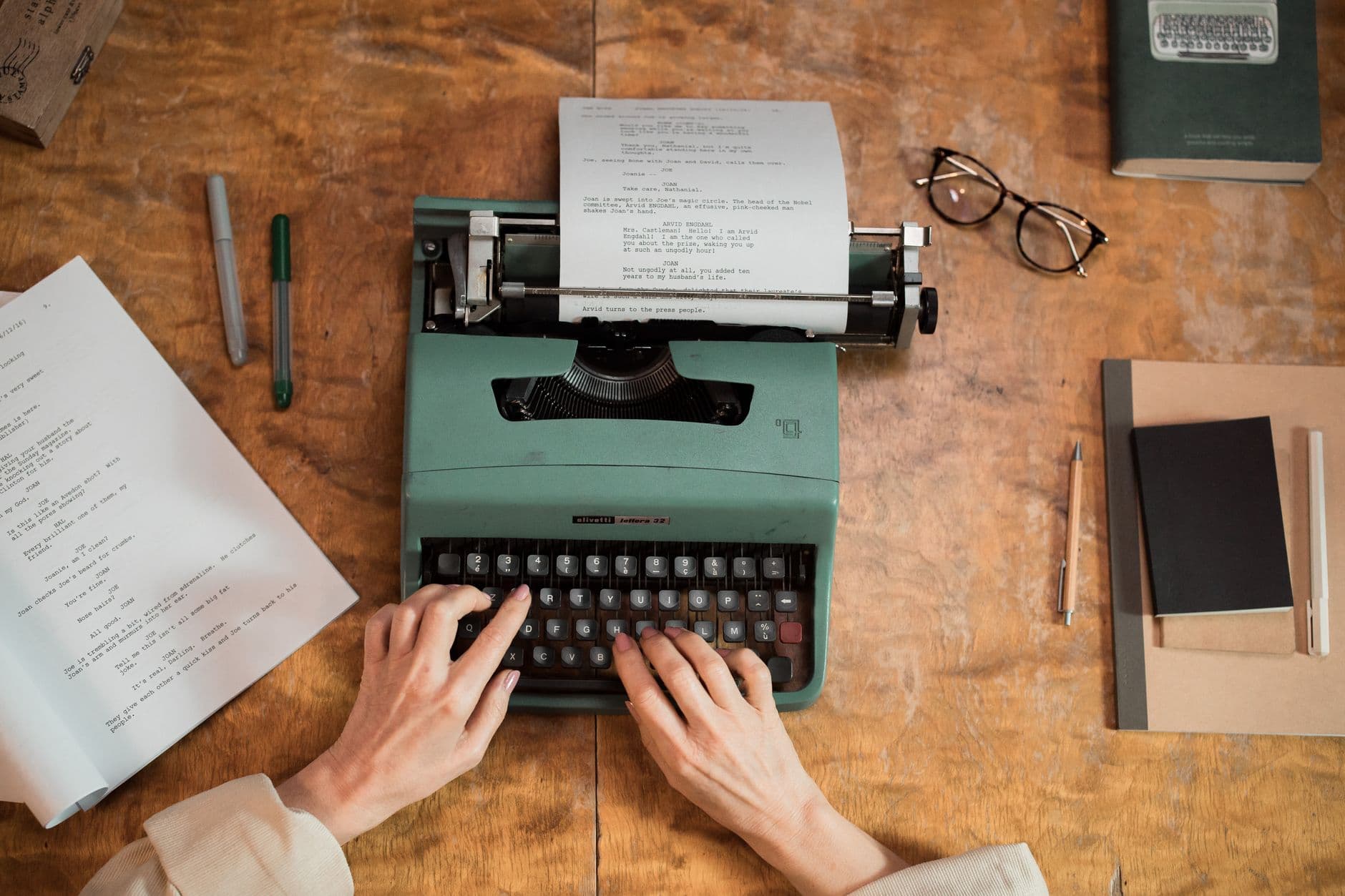 Hands typing on a typewriter with script pages for faceless YouTube content strategy.