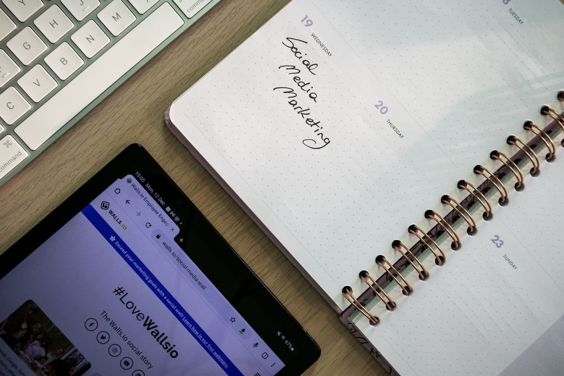 Tablet displaying social media marketing content next to a planner and keyboard for faceless YouTube strategy.