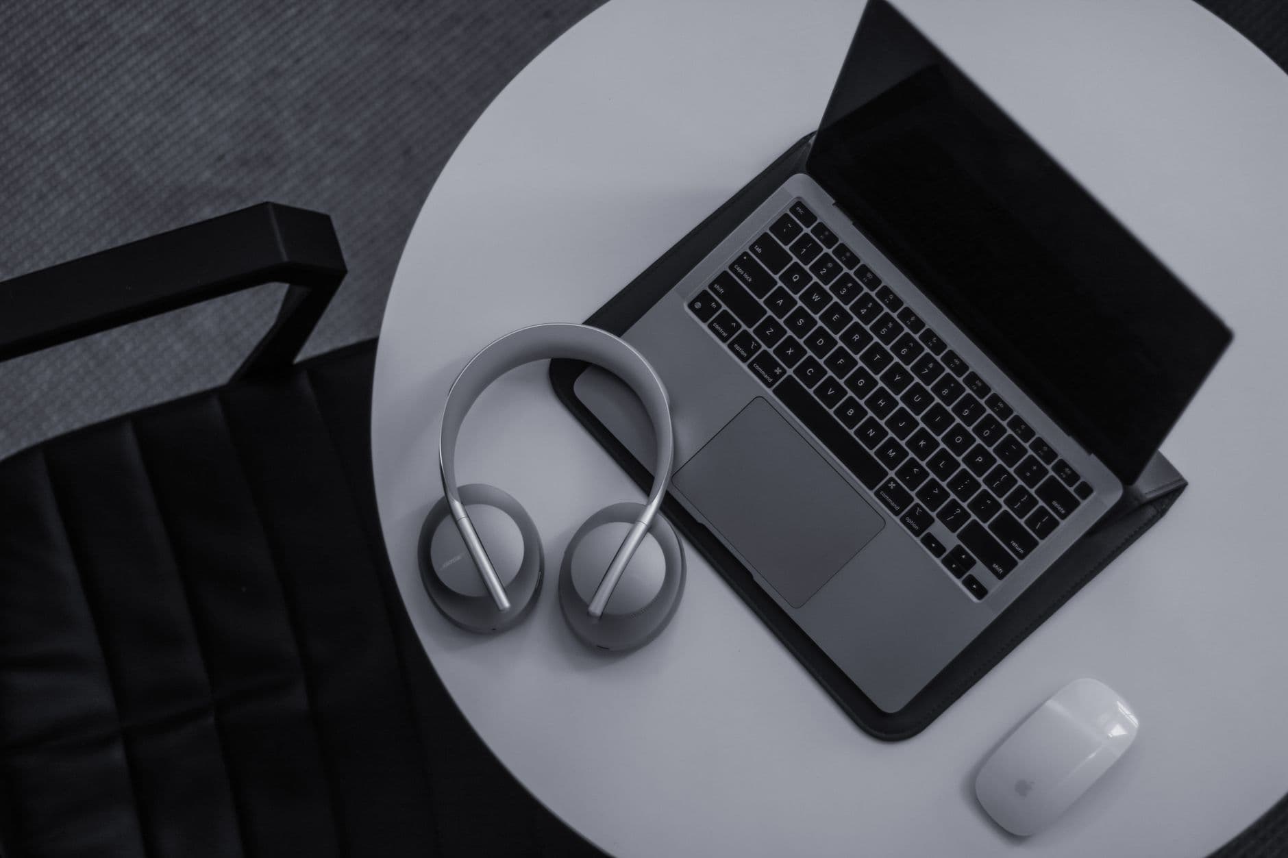 Overhead view of a laptop, headphones, and mouse on a white desk, suggesting a creator's workspace.