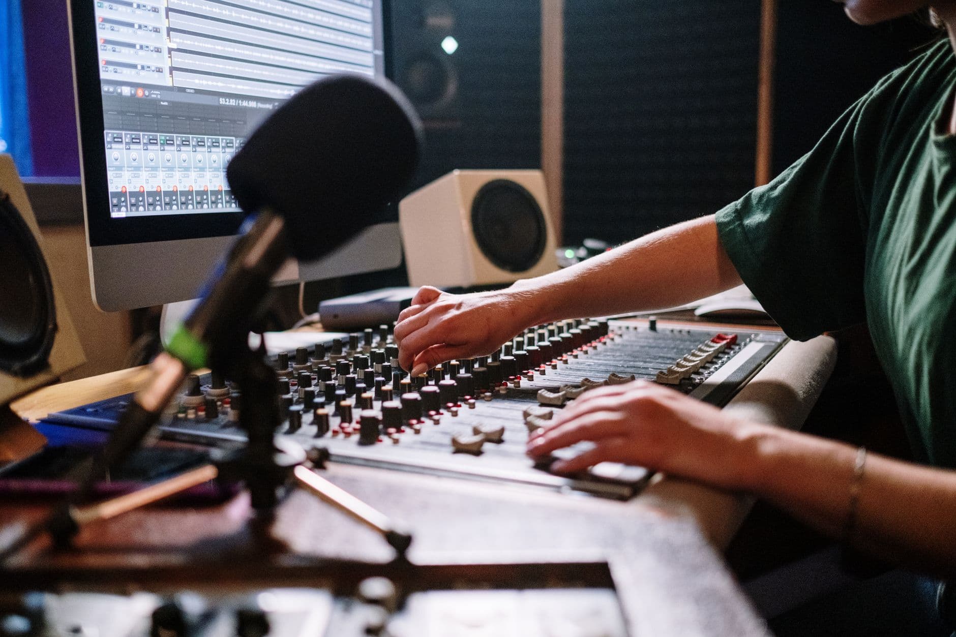 Hands adjusting audio mixer controls in a studio for faceless YouTube content creation.