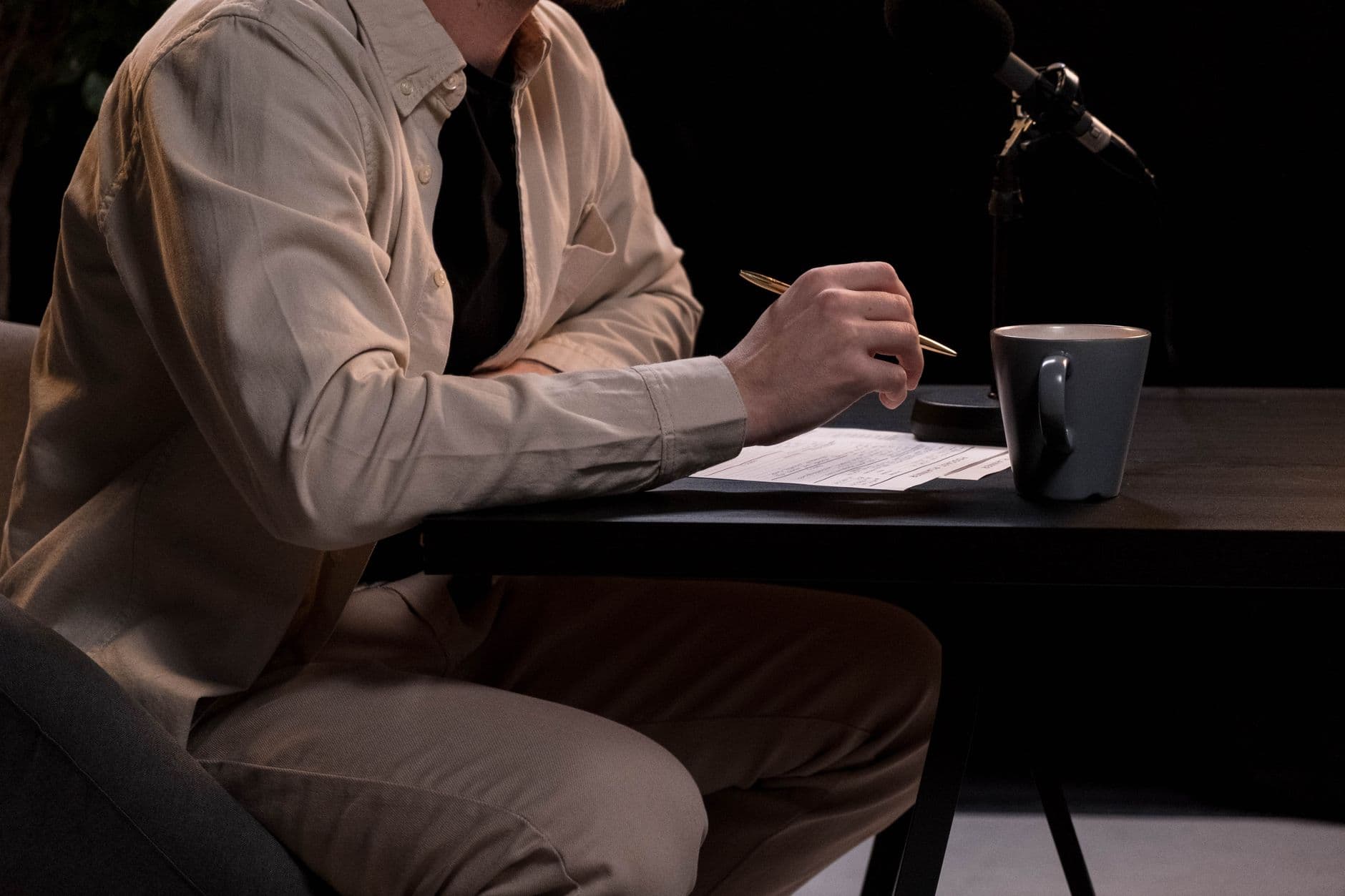 Hands adjusting a microphone for faceless YouTube content creation in a studio.