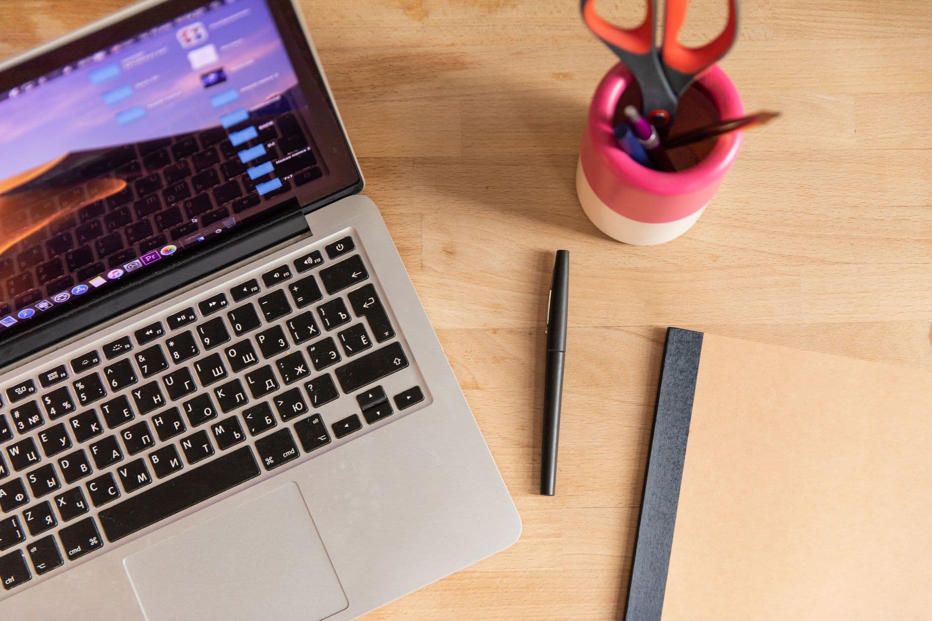 Laptop with YouTube interface open, notebook, and pen on a wooden desk for content creation strategy.
