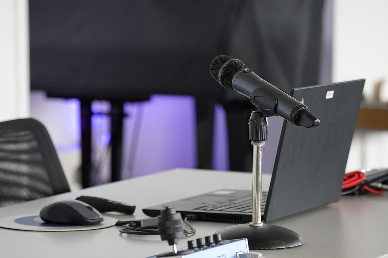 Close-up of a microphone and laptop on a desk, ideal for faceless YouTube creator workspace.