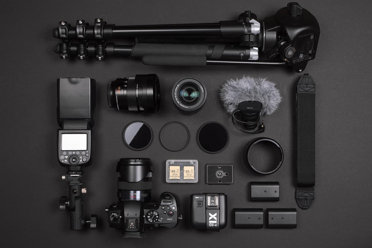 Flat lay of camera gear including a camera, lenses, flash, and tripod for faceless YouTube content creation.