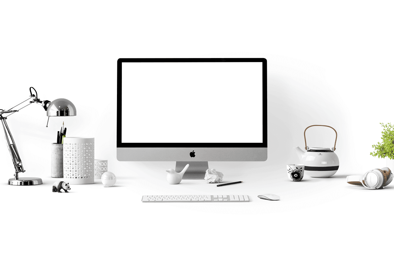 Clean desk with iMac, keyboard, and headphones for faceless YouTube channel content creation.
