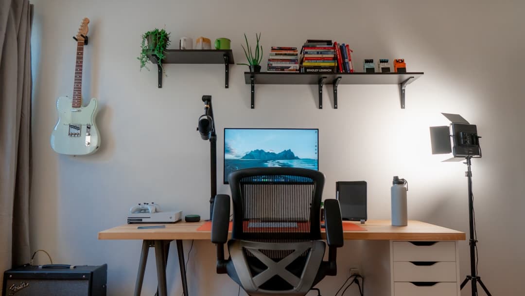 Faceless YouTube creator's desk setup with monitor displaying analytics and recording equipment.