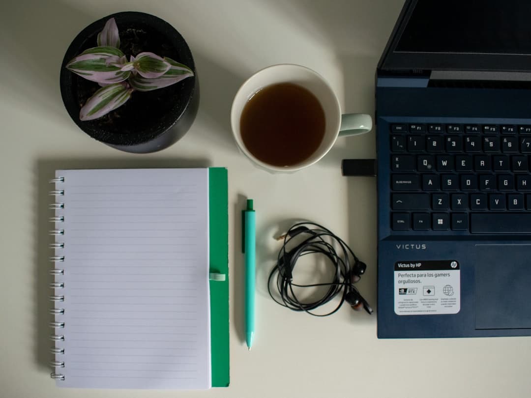 Faceless YouTube creator's workspace with laptop, notebook, and coffee for content planning.