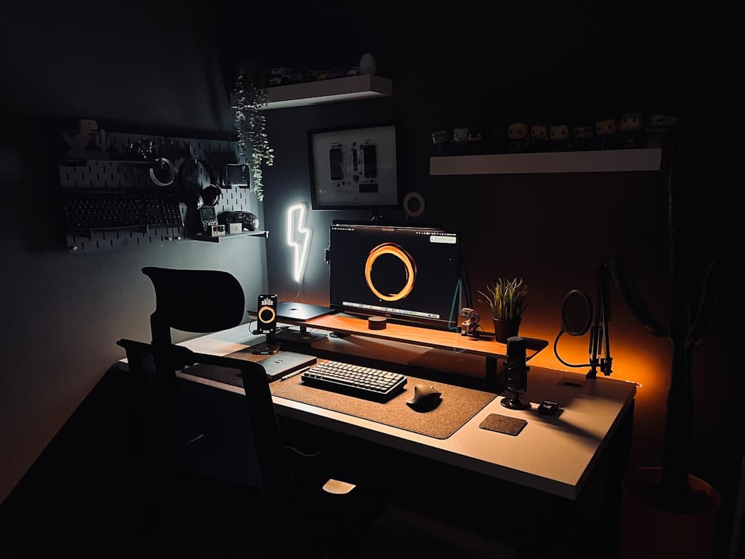 Faceless YouTube creator's dark, organized desk setup with multiple monitors and audio equipment.