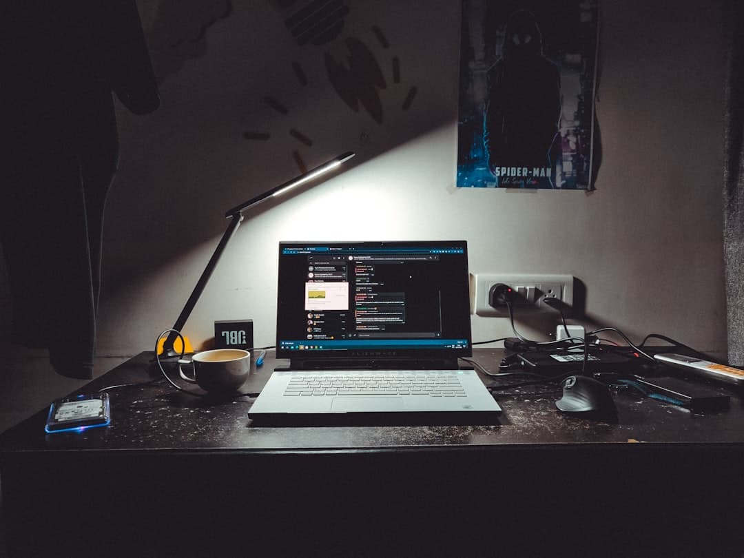 Faceless YouTube creator's desk with laptop showing analytics and a lamp.