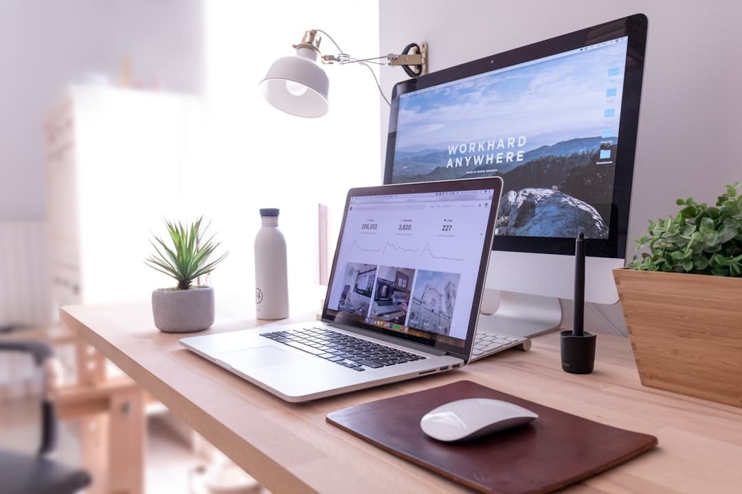 Desk setup with laptop and monitor displaying analytics for faceless YouTube channel workflow.
