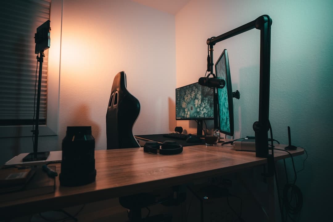 Faceless YouTube creator's desk setup with monitors, microphone, and lighting.