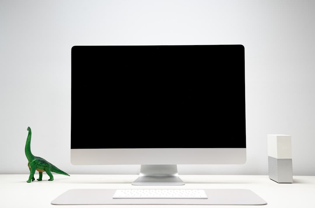 Faceless YouTube creator's desk with a blank monitor and keyboard, suggesting workflow setup.