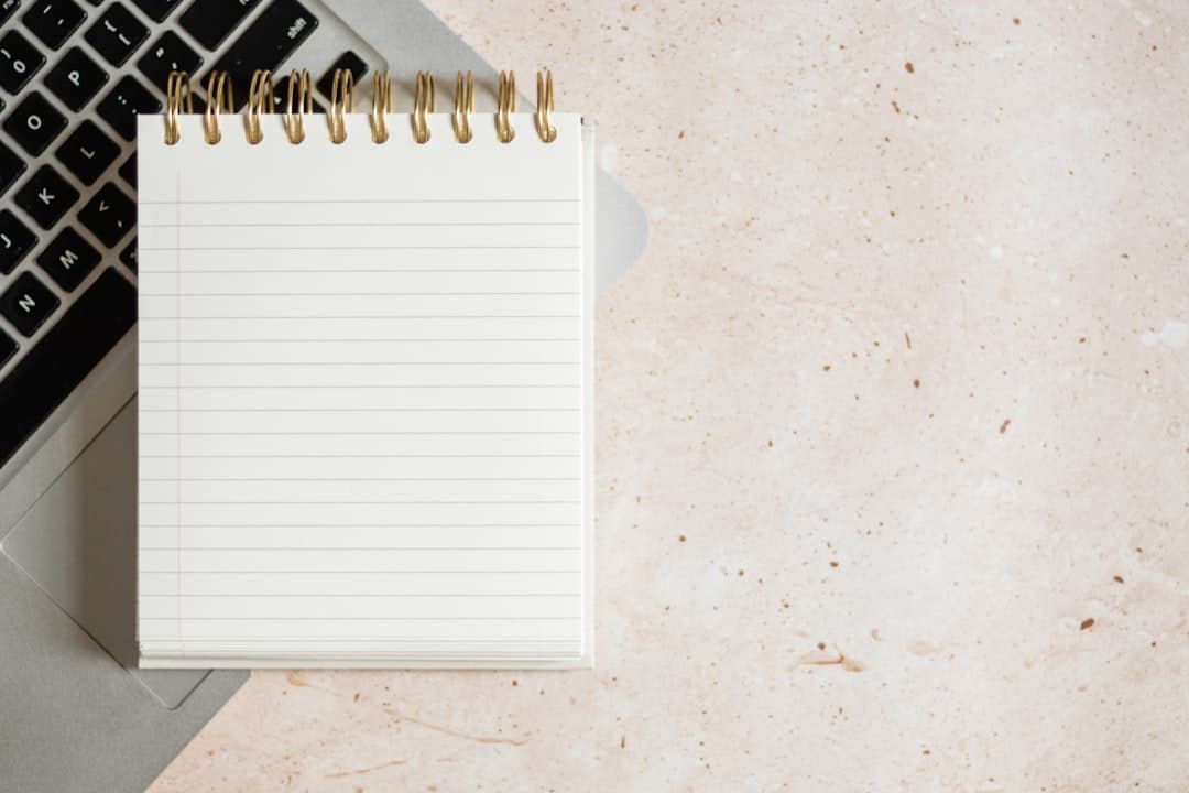 Faceless YouTube creator's notebook and laptop for workflow planning and content strategy.