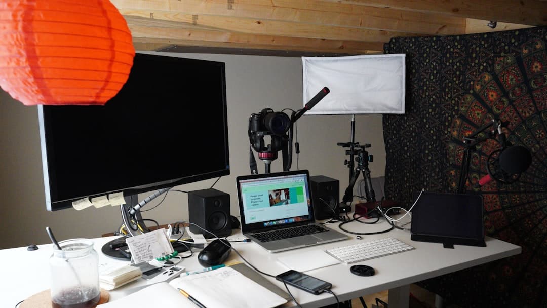 Faceless YouTube creator's desk with multiple monitors, camera, and microphones for content production.