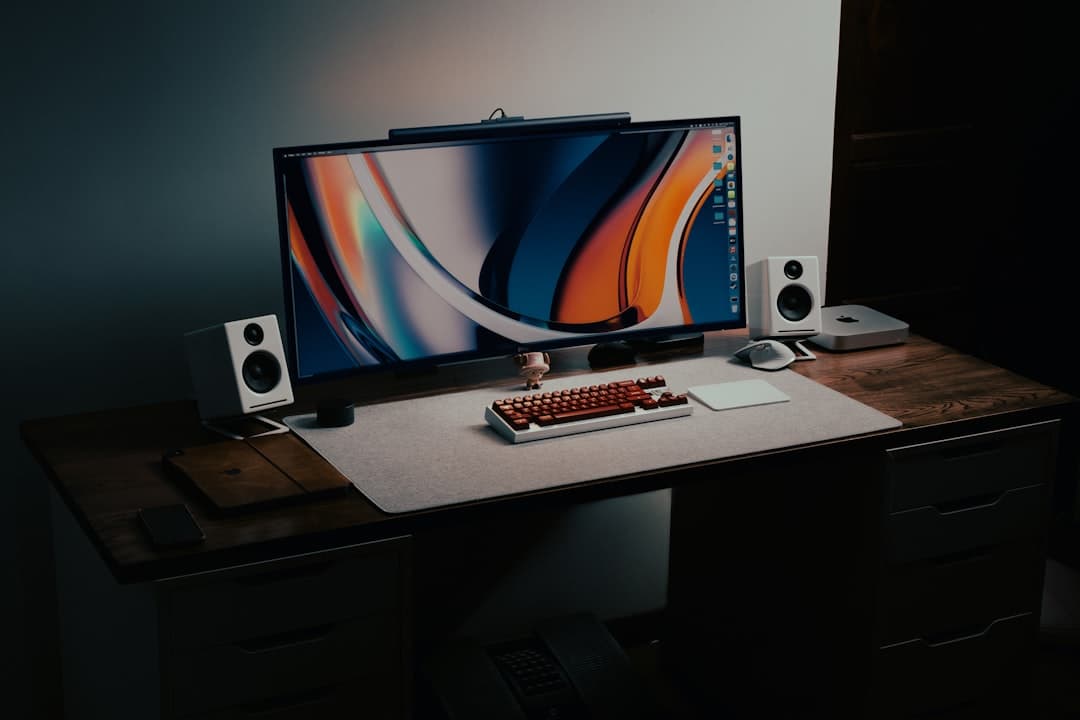 Faceless YouTube creator's desk setup with monitor, keyboard, and speakers.