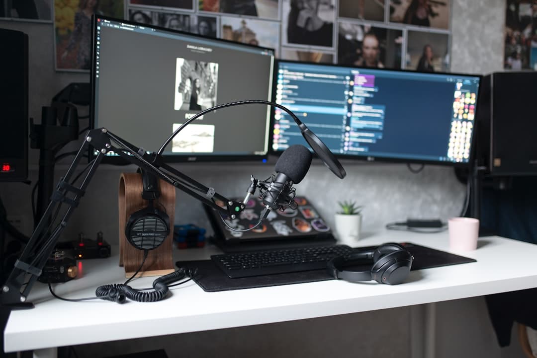 Faceless YouTube creator's desk with dual monitors, microphone, and headphones for content production.