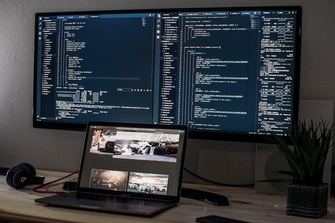 Dual monitors displaying code and website design, with a laptop on a desk for content creation.
