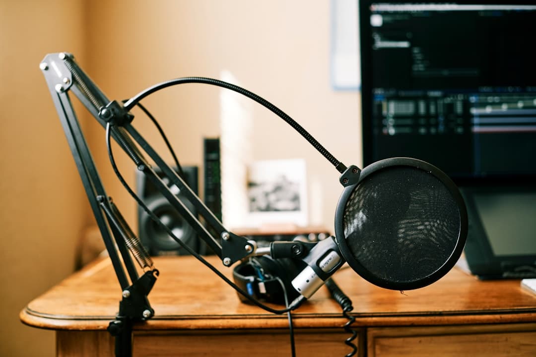 Faceless YouTube creator's desk with microphone, pop filter, headphones, and monitor showing video editing timeline.