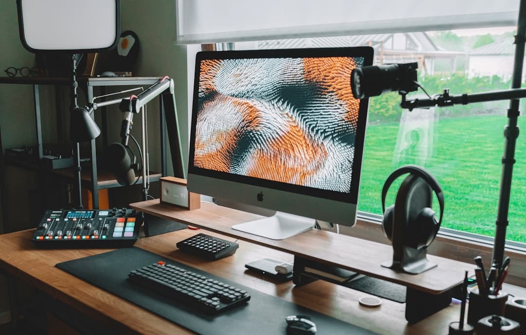Faceless YouTube creator's desk with computer, microphone, and headphones for AI tool stack audit.