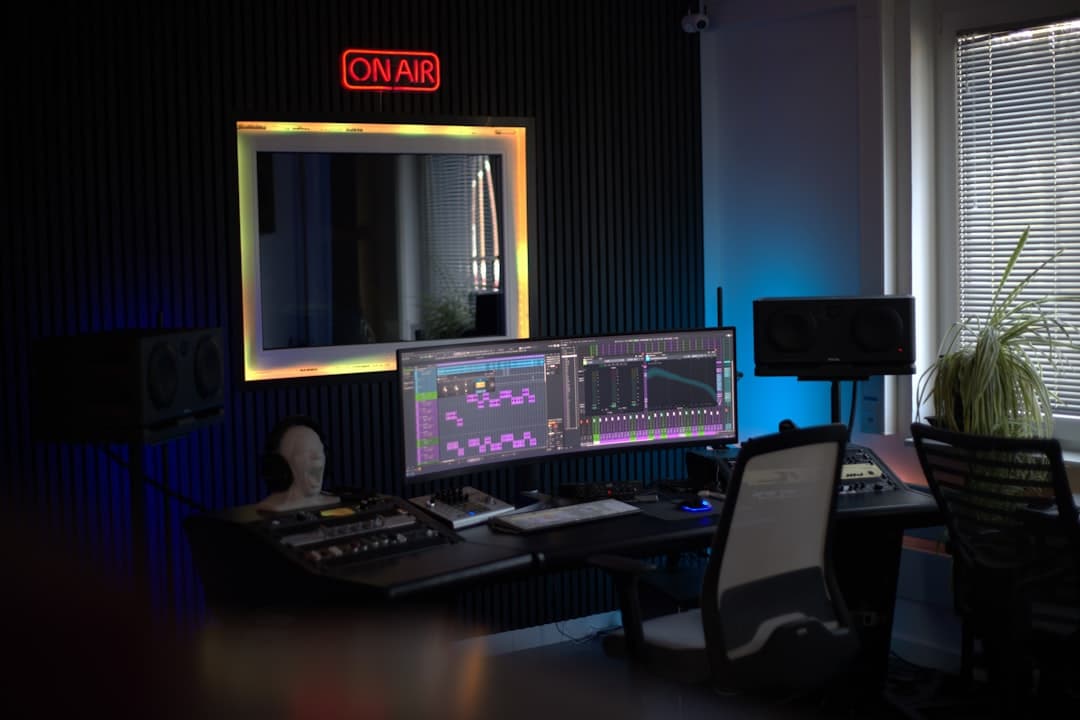 Faceless YouTube creator's studio with dual monitors displaying video editing software and audio equipment.