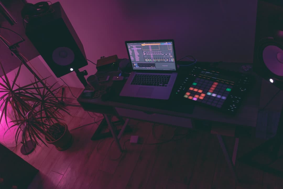 Faceless YouTube creator's desk with laptop, MIDI controller, and studio monitors for AI stack auditing.