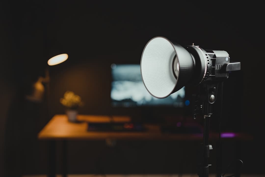 Studio lighting equipment set up in a dark room with a blurred desk and monitor in the background.