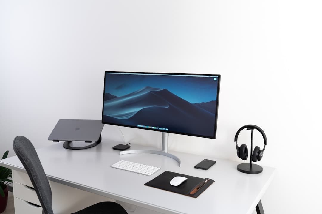 Clean desk setup with monitor displaying desktop, laptop, headphones, and keyboard for faceless YouTube channel content strategy.