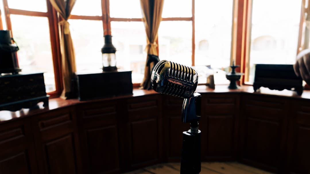 Vintage microphone on a stand in a room with large windows, suggesting a recording setup for a faceless YouTube creator.