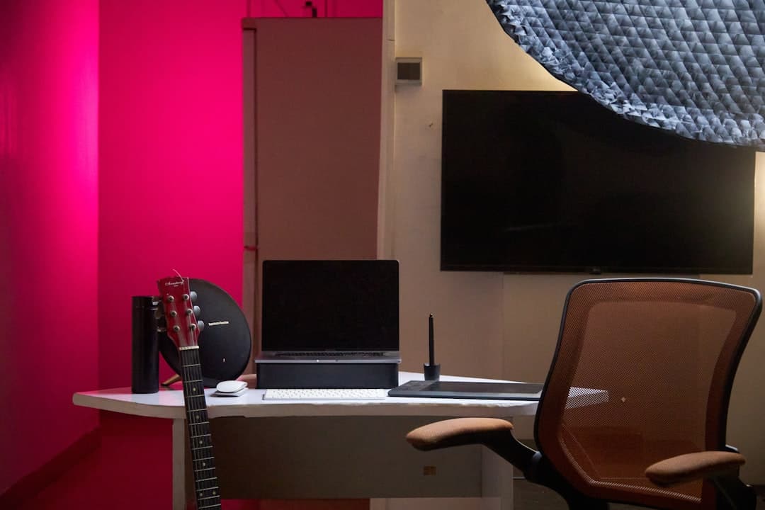 Faceless YouTube creator's desk with laptop, monitor, and audio equipment for AI tool auditing.