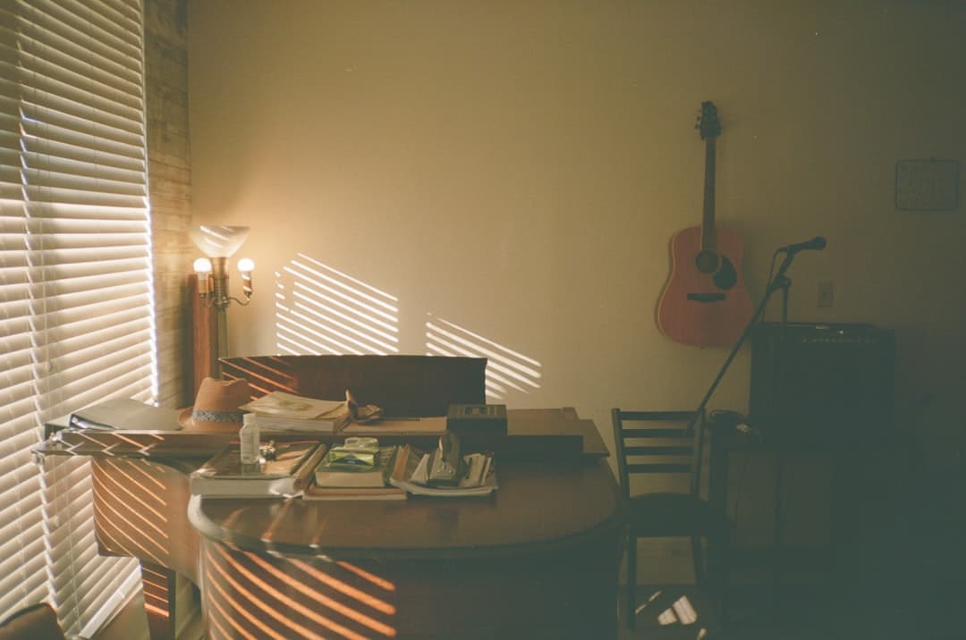 Faceless YouTube creator's desk with guitar, microphone, and books, suggesting a creative workspace.