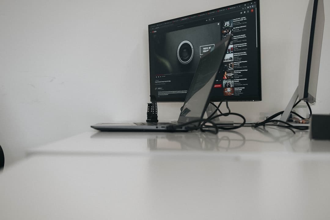 Faceless YouTube creator's desk with multiple monitors displaying analytics and video editing software.