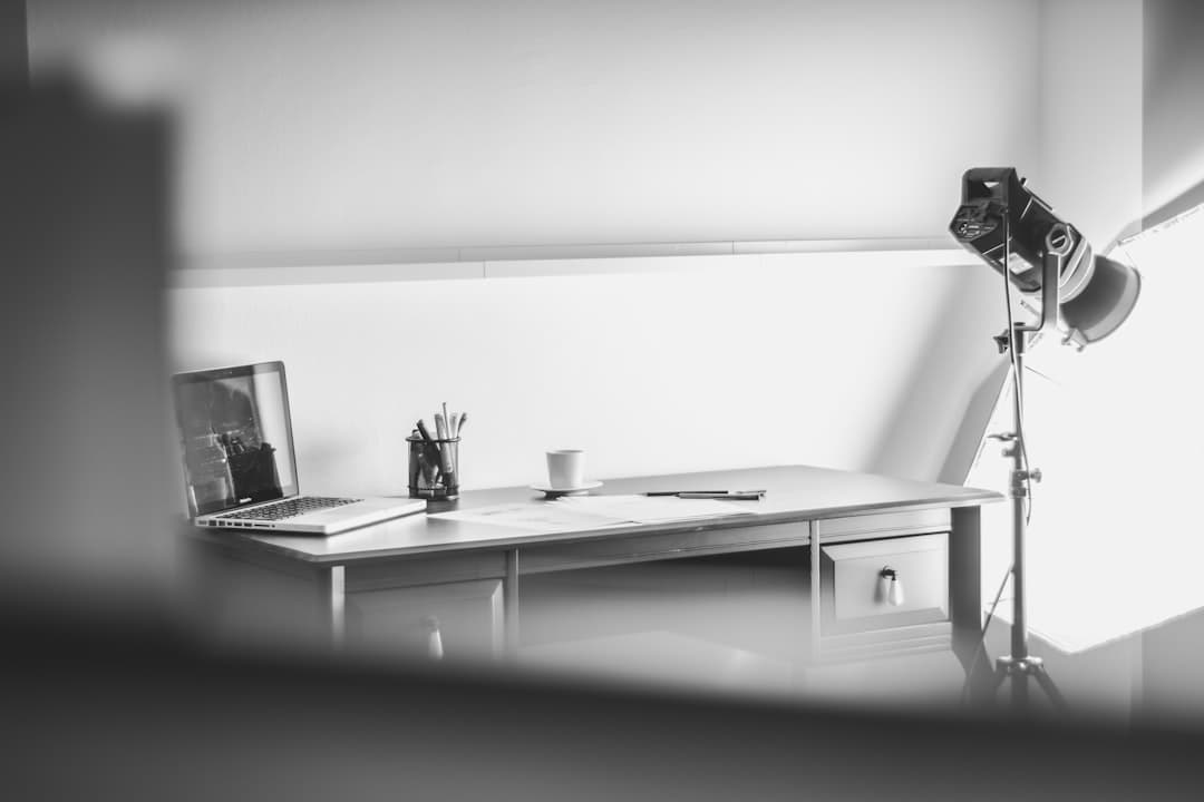 Faceless YouTube creator's desk with laptop, microphone, and lighting setup for video production.
