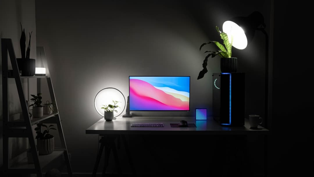 Faceless YouTube creator's desk setup with computer monitor, plants, and lighting.