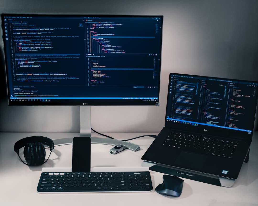Dual monitors and laptop displaying code and analytics for a faceless YouTube creator's workflow.