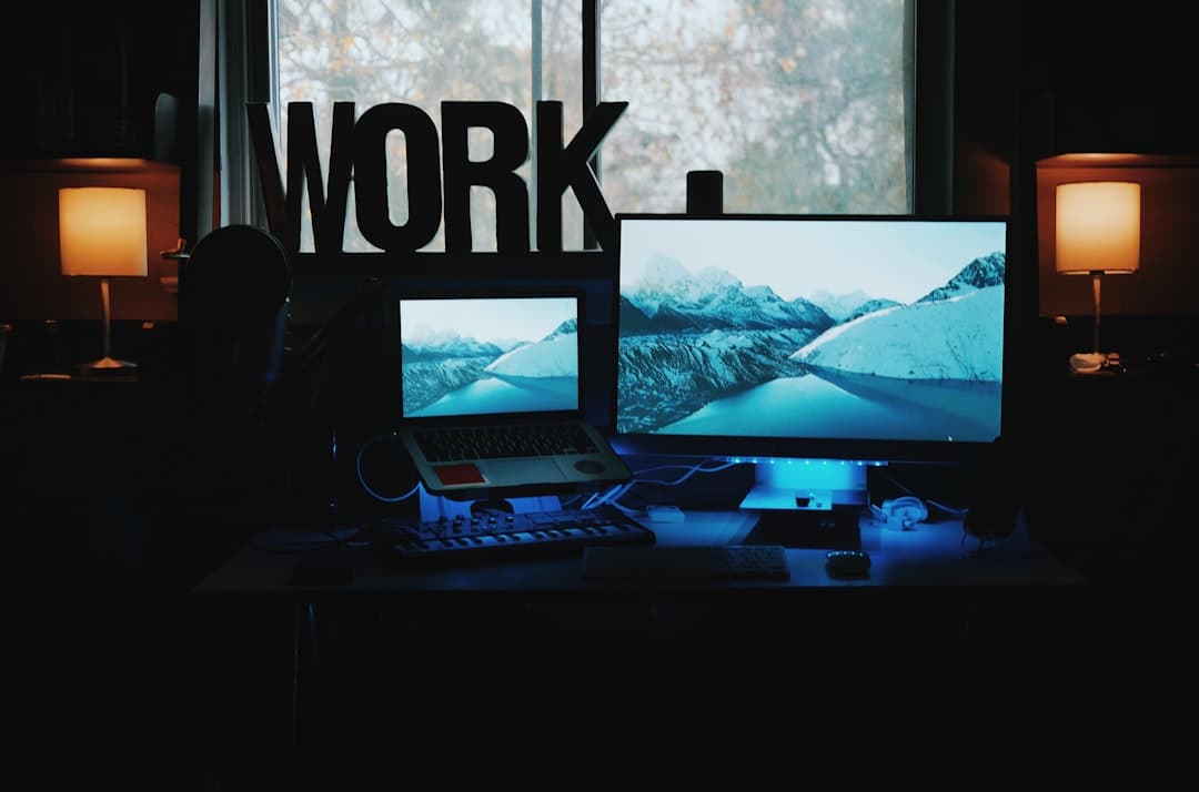 Faceless YouTube creator's desk setup with dual monitors and laptop, suggesting a content creation workflow.