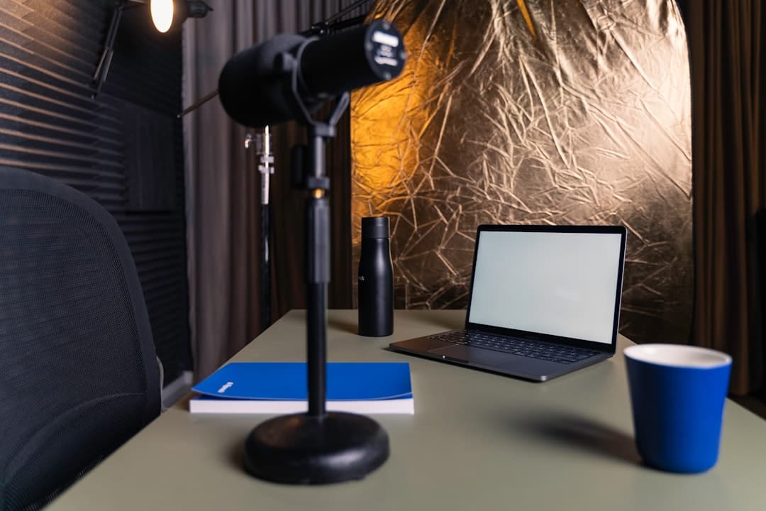 Faceless YouTube creator's desk with laptop, microphone, and notebook for visual storytelling.