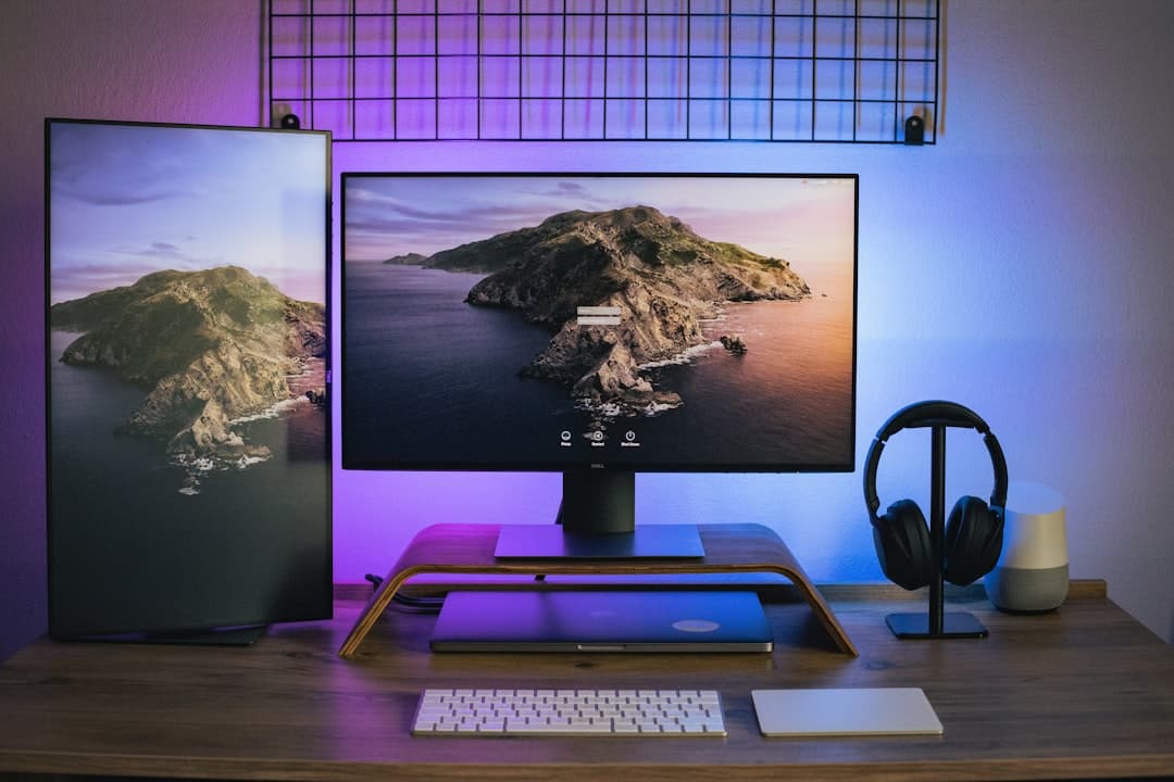Desk setup with dual monitors, laptop, and headphones for faceless YouTube content creation.