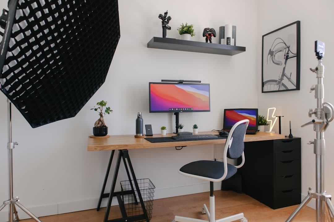 Faceless YouTube creator's desk setup with monitors, laptop, and lighting for video production.
