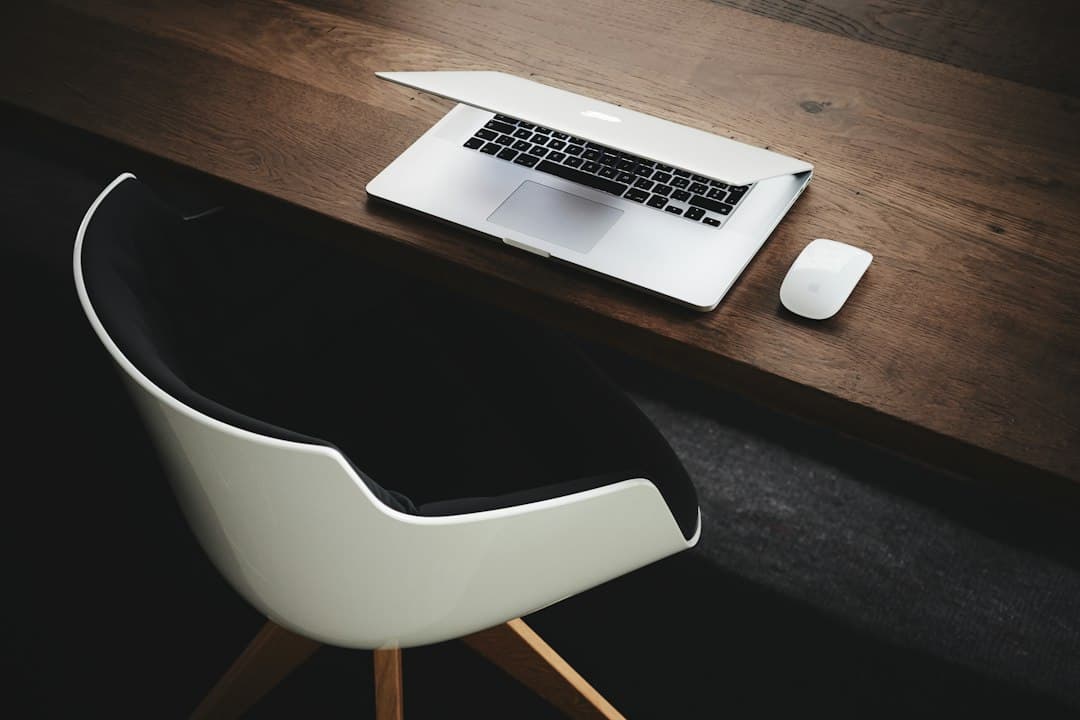 Faceless YouTube creator's desk with open laptop and mouse, suggesting workflow.