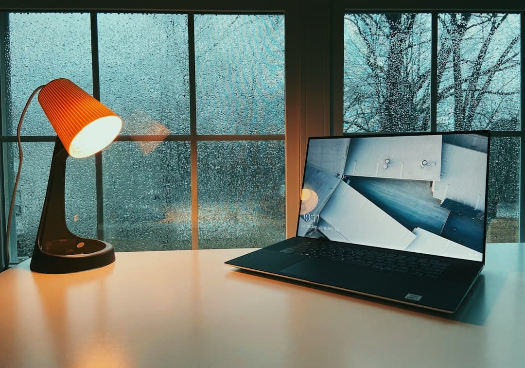 Faceless YouTube creator's desk with laptop and lamp, suggesting a workspace for content creation.