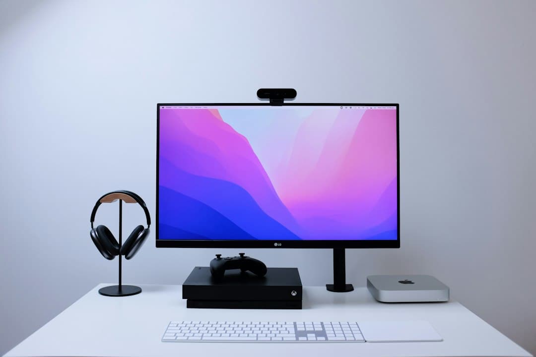 Clean desk setup with monitor displaying abstract art, headphones, and a gaming console for faceless YouTube content creation.