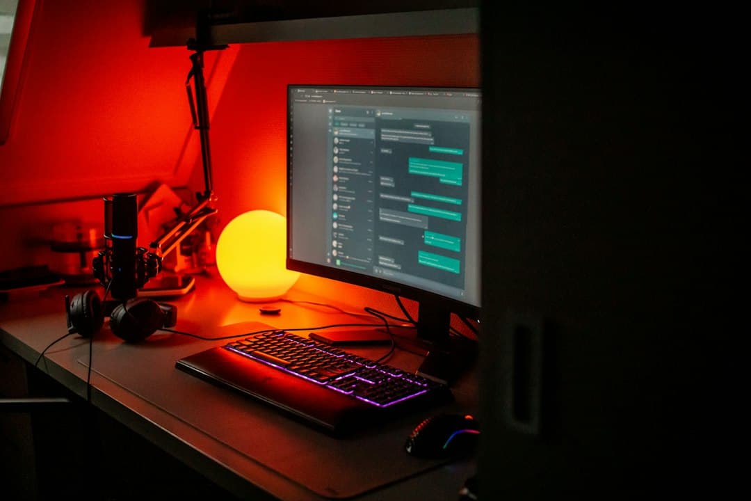 Faceless YouTube creator's desk with monitor showing chat, microphone, and keyboard.