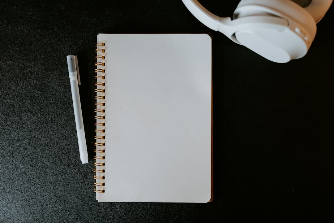 Faceless YouTube creator's planning notebook and headphones for competitor analysis.