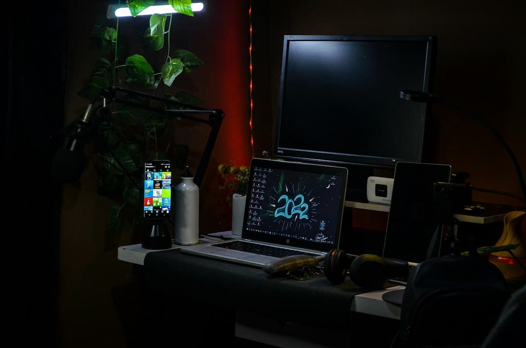 Faceless YouTube creator's desk with laptop, monitors, and microphone for AI stack audit.